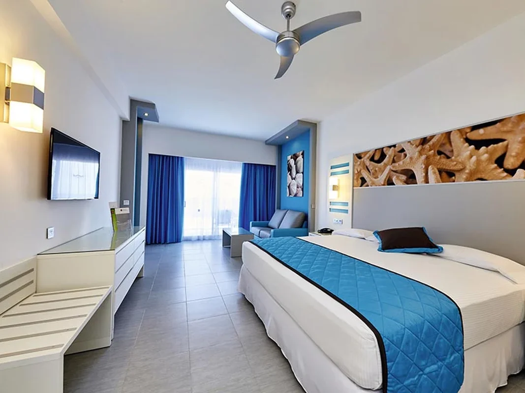 Guest room with blue accents and balcony at Hotel Riu Republica in Punta Cana
